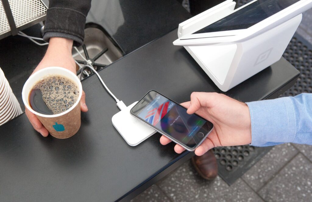 An iPhone being used to make a contactless payment at a reader