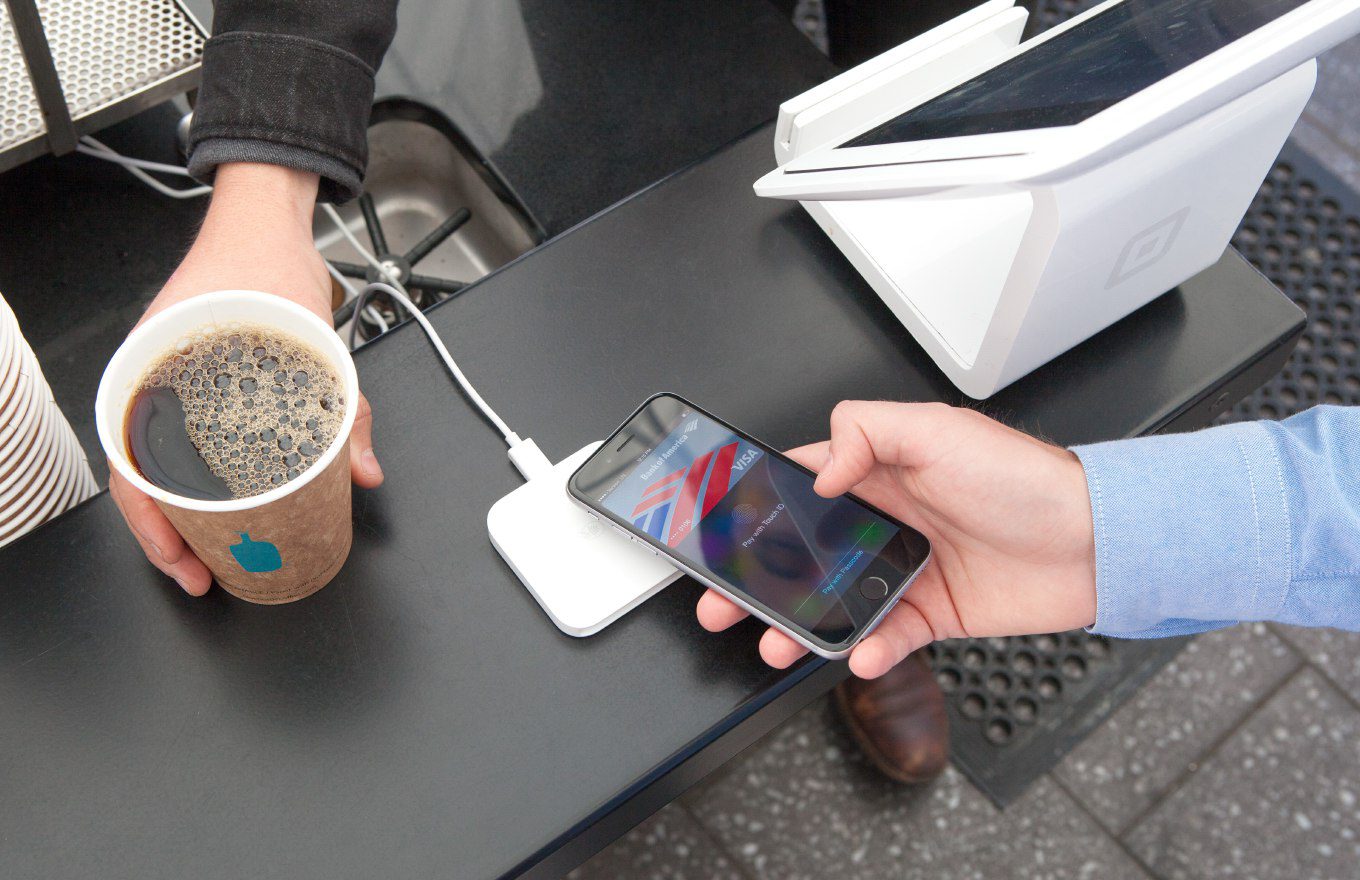 An iPhone being used to make a contactless payment at a reader